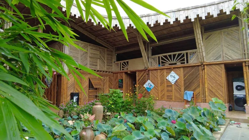 Nhà vách tre đan bên hồ sen và vườn hoa